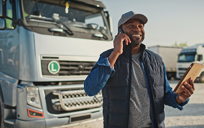 Trucker speaks on mobile phone while looking at his telematics safety gamification score.